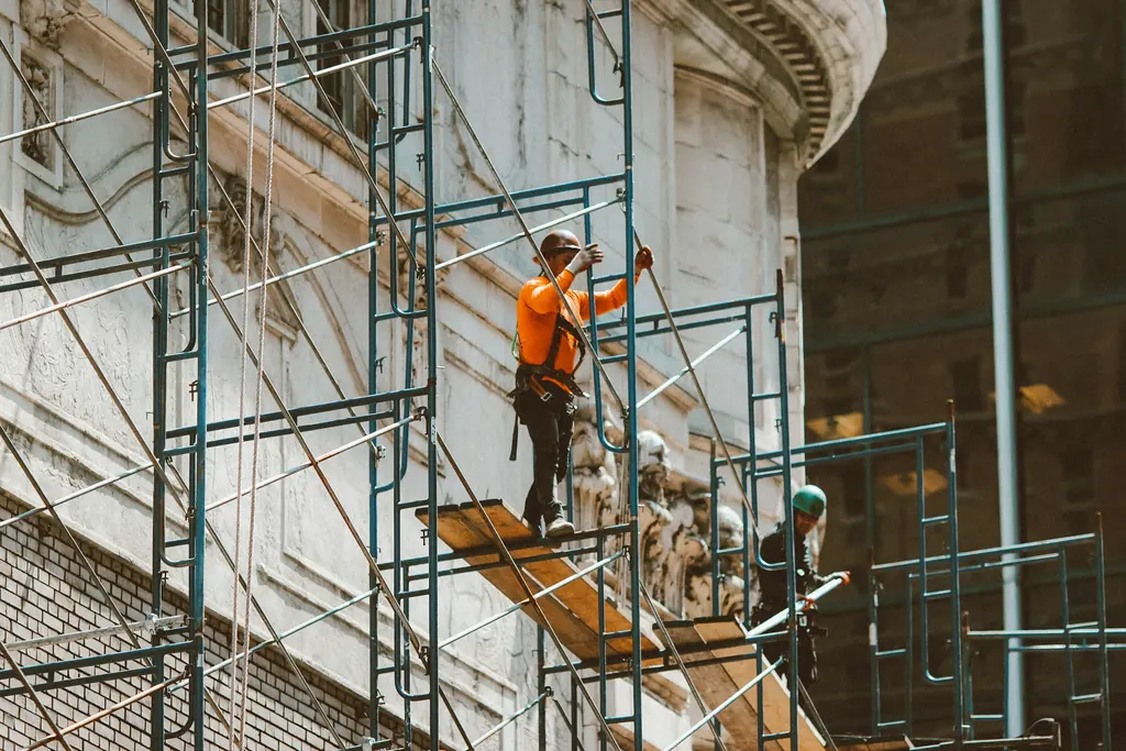Trabajador en andamio dando mantenimiento a la fachada de un edificio